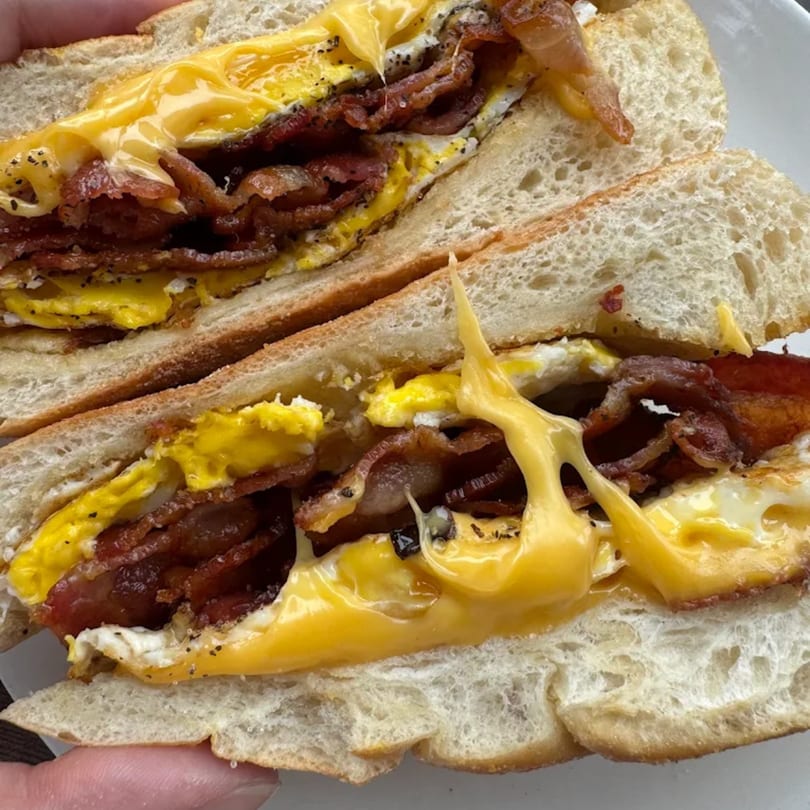 A Mr Donkey breakfast burrito, cut in half, filled with scrambled eggs, crispy bacon, and melted cheese.