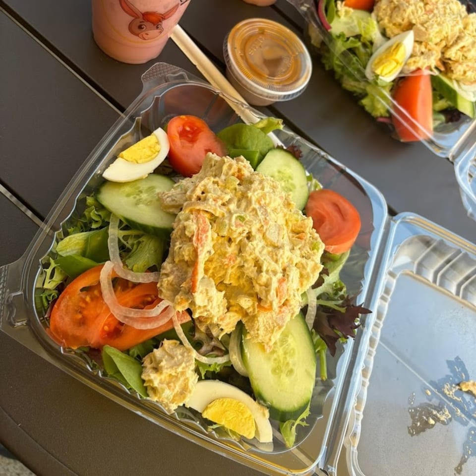 Two Mr Donkey salads with chicken, hard-boiled eggs, tomatoes, cucumbers, and onions in plastic containers.