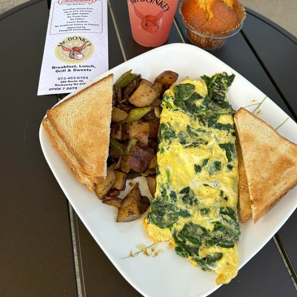 A Mr. Donkey breakfast plate with a spinach omelet, home fries, toast, and a drink.